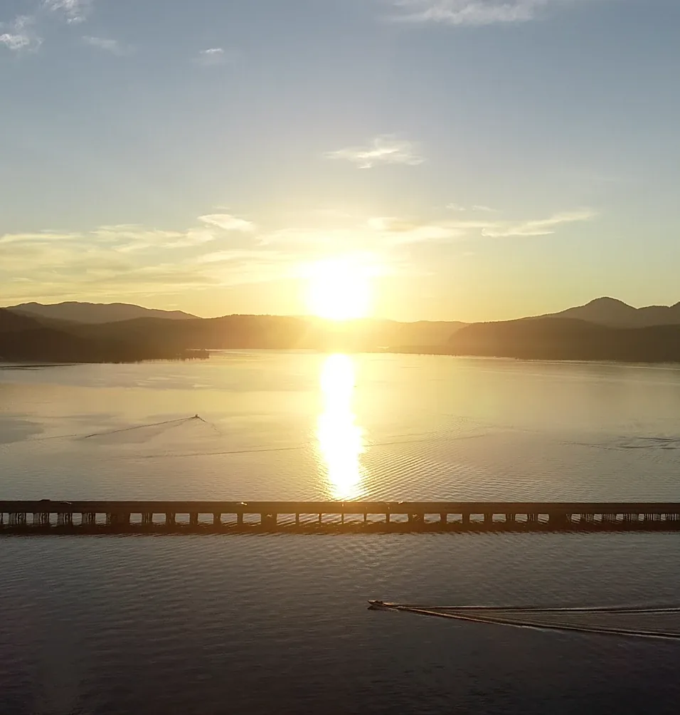 Sunset over Lake Pend Oreille in Sandpoint, Idaho, from the air, with a boat crossing below the bridge